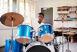 Male Teenage Pupil Playing Drums In Music Lesson