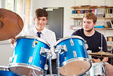 Male Pupil With Teacher Playing Drums In Music Lesson