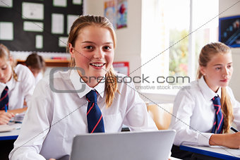 Portrait Of Female Pupil In Uniform Using Laptop In Classroom