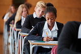 Teenage Students In Uniform Sitting Examination In School Hall