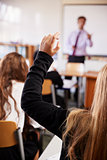 Female Student Raising Hand To Ask Question In Classroom