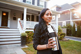 Businesswoman With Cup Of Coffee Leaving Suburban House For Work