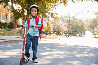 Young Boy Riding Scooter Along Street To School