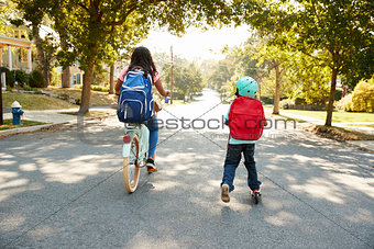 Sister With Brother Riding Scooter And Bike To School