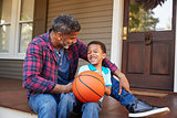 Father And Son Discussing Basketball On Porch Of Home