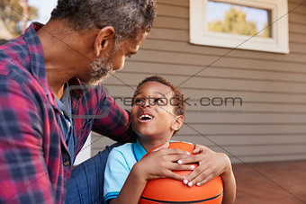 Father And Son Discussing Basketball On Porch Of Home