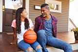 Father And Daughter Discussing Basketball On Porch Of Home