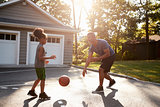 Father And Son Playing Basketball On Driveway At Home
