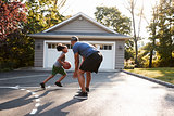 Father And Son Playing Basketball On Driveway At Home