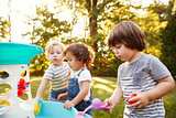 Group Of Young Children Playing With Water Table In Garden
