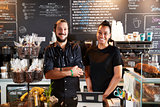 Male And Female Baristas Behind Counter In Coffee Shop