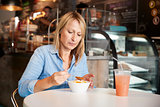 Woman In Coffee Shop Sitting At Table Eating Bowl Of Soup