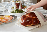 Hand placing dish on table set for Jewish Shabbat, close up
