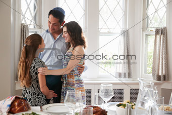 Jewish couple and daughter embracing before Shabbat meal