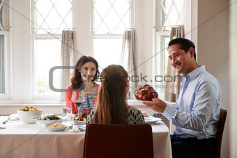 Jewish man holding challah bread at Shabbat meal with family