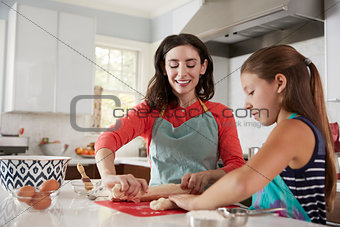 Jewish mother and daughter rolling dough for challah bread