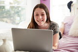 Teenage girl lying on bed using a laptop computer, close up
