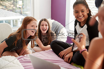 Four teen girls in bedroom looking at smartphone, close up