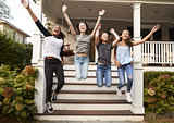 Four young teen girls jumping from front steps of a house