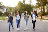 Four young teen girls walking in the road, full length