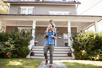Father Giving Son Ride On Shoulders Outside House