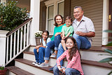 Grandparents With Grandchildren Sit On Steps Leading Up To Home