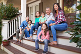 Multi Generation Family Sit On Steps Leading Up To House Porch