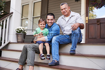 Male Multi Generation Family Sitting On Steps in Front Of House