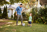 Father Playing Soccer In Garden With Son