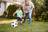 Grandfather Playing Soccer In Garden With Grandson