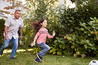 Grandfather Playing Soccer In Garden With Granddaughter