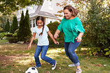 Grandmother Playing Soccer In Garden With Granddaughter