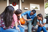 Family Carving Halloween Pumpkin On House Steps