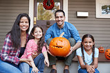 Portrait Of Family Carving Halloween Pumpkin On House Steps