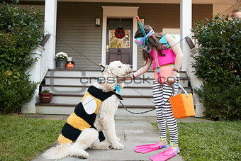 Girl With Dog Wearing Halloween Costumes For Trick Or Treating
