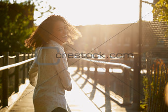 Young Woman Walking Along Bridge In Urban Setting