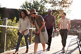 Group Of Friends Walking Along Bridge In Urban Setting