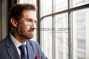 Senior white businessman looking out of window, close up