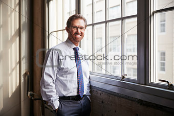 Senior businessman with hands in pockets smiling to camera