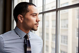 Young Hispanic business man looking out of window