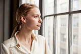 Young blonde businesswoman looking out of window