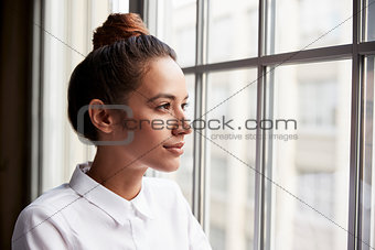 Young businesswoman with hair bun looking out of window