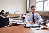 Businessman working at desk, female colleagues in background