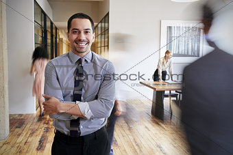 Portrait of young Hispanic man in a busy modern workplace