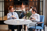 Male and female colleagues talk over coffee at office cafe