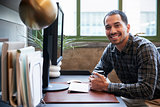 Hispanic man at a computer in an office smiling to camera