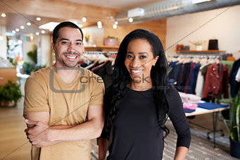 Young adult couple smiling to camera in a clothes shop