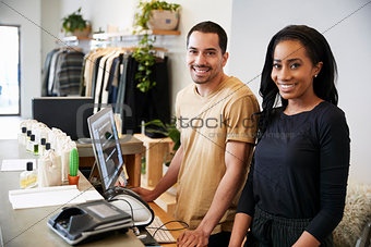 Smiling colleagues behind the counter in clothing store