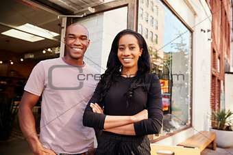 Young couple smiling to camera outside their clothes shop