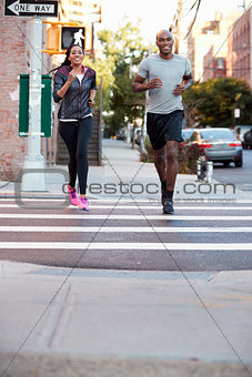 Young black couple jogging in Brooklyn, vertical